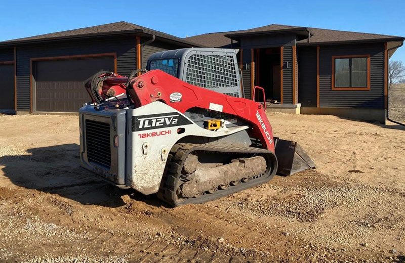 A skidsteer sitting in front of a new home