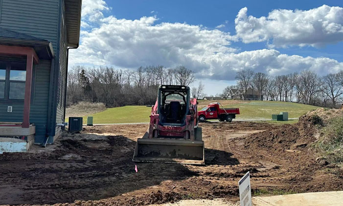 skidsteer Skidsteer in front of a new home with the grading finished by Davis Construction